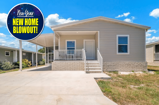 Single-story manufactured home with a front porch, carport, and driveway, shown under a blue sky. Circular "New Year New Home Blowout!" sign in the top left corner.